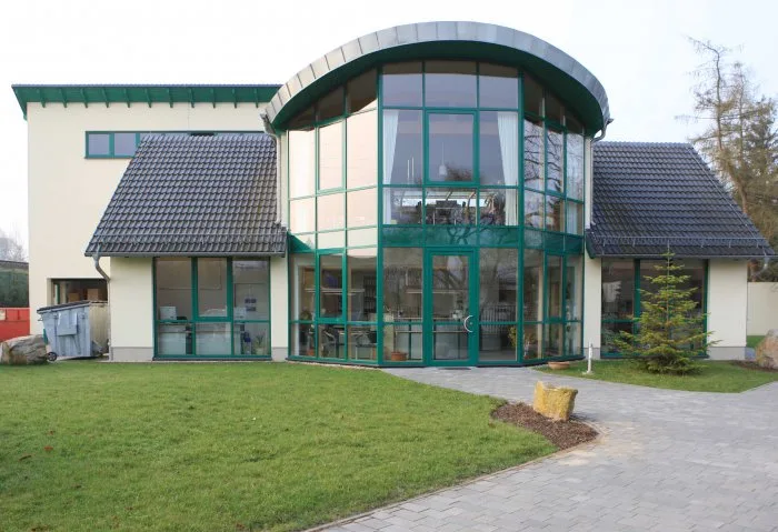 Firmengebäude der BERNA Kühlanlagen GmbH mit grüner Glasrotunde und gepflasterter Auffahrt